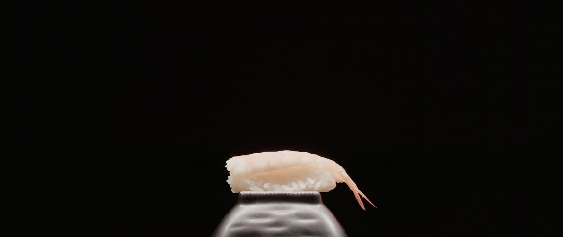 Shellfish sits on overturned bowl in dark room