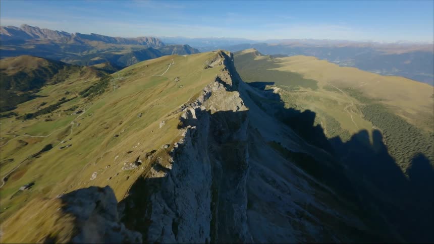 A jagged steeply sloped green mountain ridge on a bright sunny day