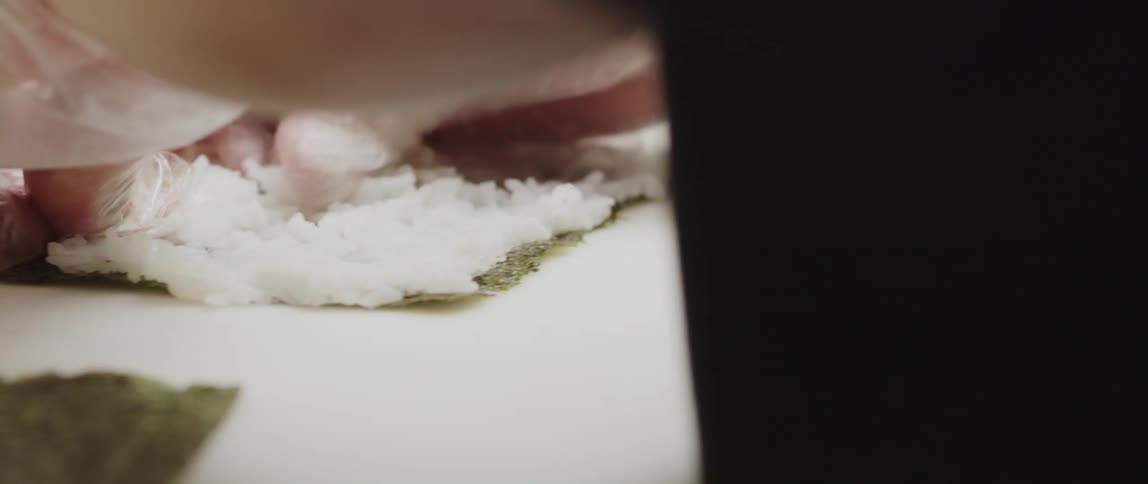 Sushi chef spreads rice on pieces of seaweed