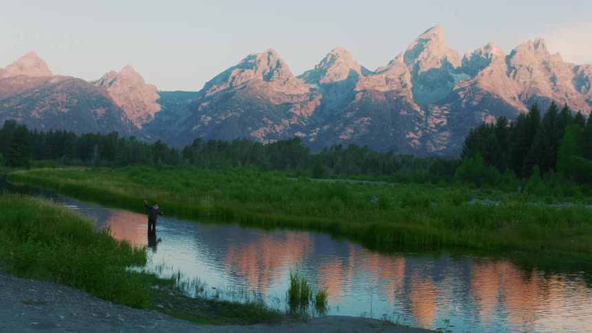 A person fishing outdoors in a river