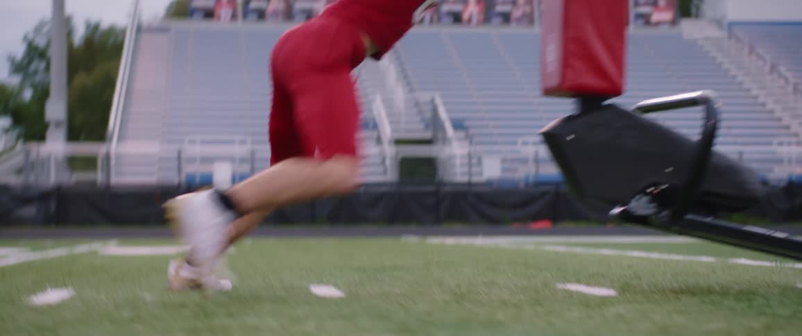 Player with red jersey does the sled push in american football stadium