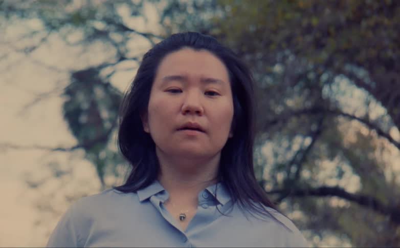 A person is standing outdoors next to a tree