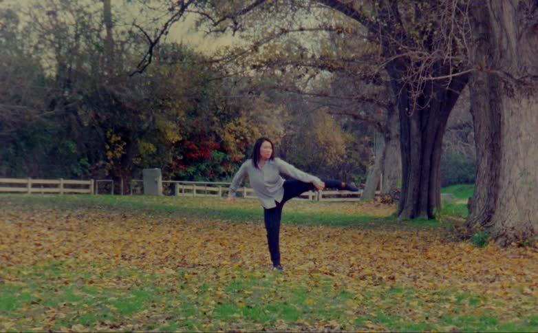 A woman is stretching her legs outdoors in autumn