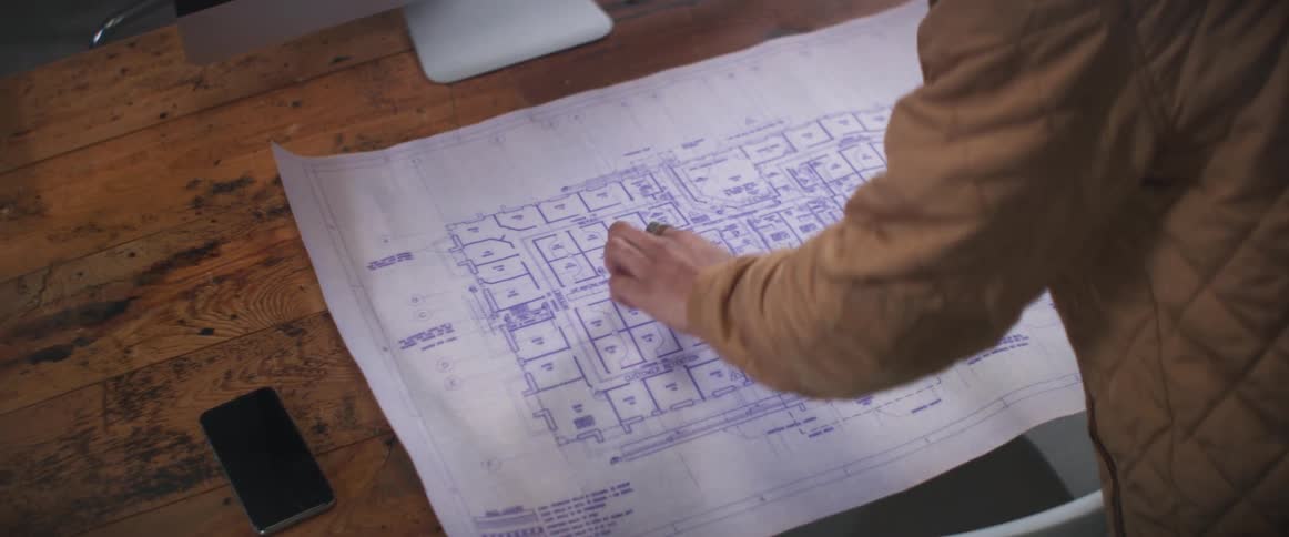 A person rolls out the blueprints on his desk