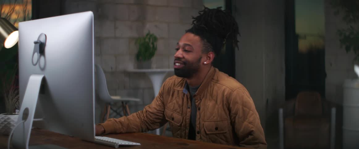 A man sits down at his desk for a video call on his computer