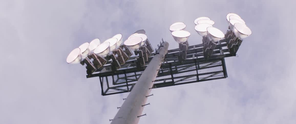 Stadium lighting towering overhead on a cloudy day