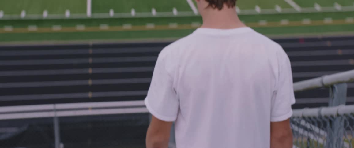 A man walking down stairs in bleachers next to a track