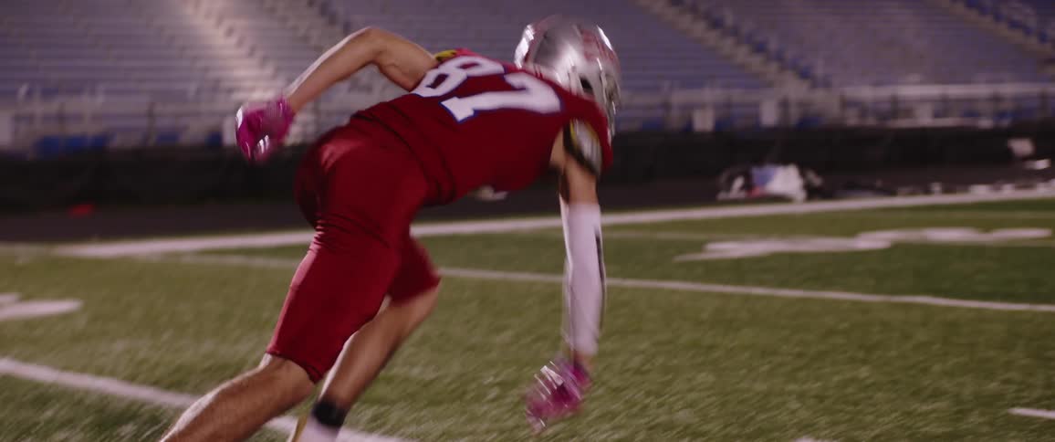 A football player practices running into a dummy in a stadium