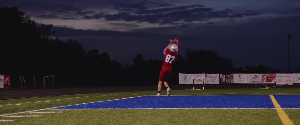 A football player runs and catches a toss during practice in a stadium