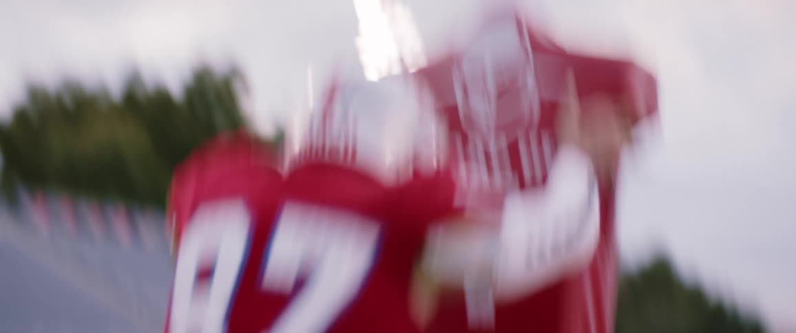 Football player wearing red uniform practices with a dummy on a stadium at evening