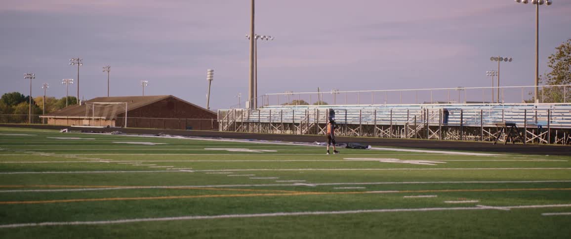 Football player leisurely walking on a football field at evening