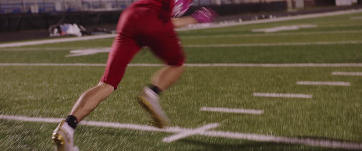 A person is practicing football on an empty field at dusk