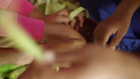 An adult and two children are preparing rice