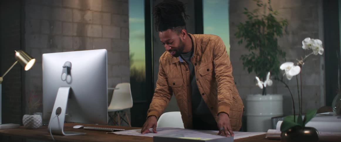 A man rolls the blueprints out on his desk