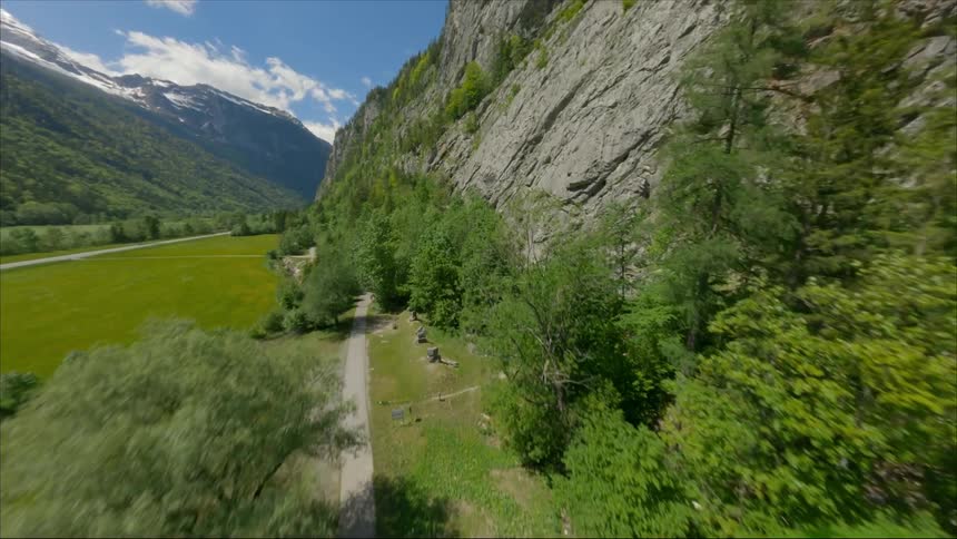 Roads and stream parallel each other as they run through valley between mountains