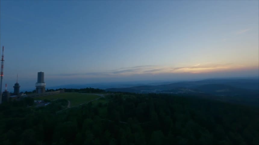 Building complex stands on hill surrounded by forest overlooking town