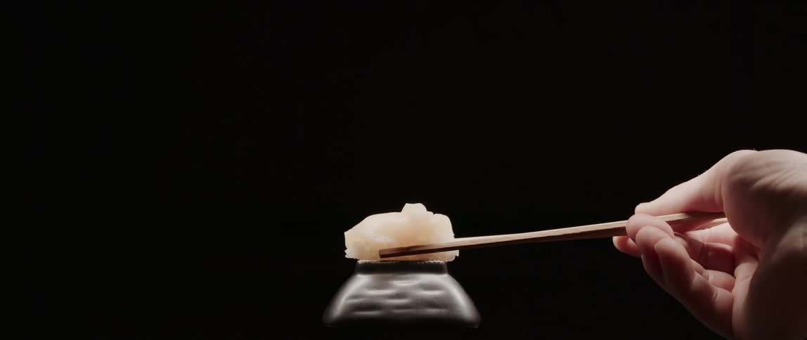 A man picks up a piece of sushi with chopsticks