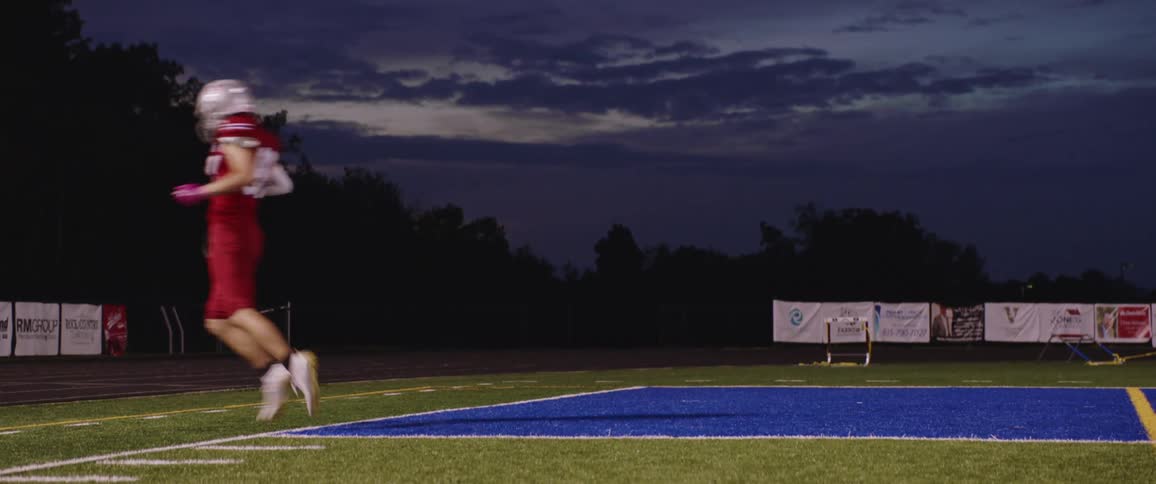 A man is practicing football outdoors at night