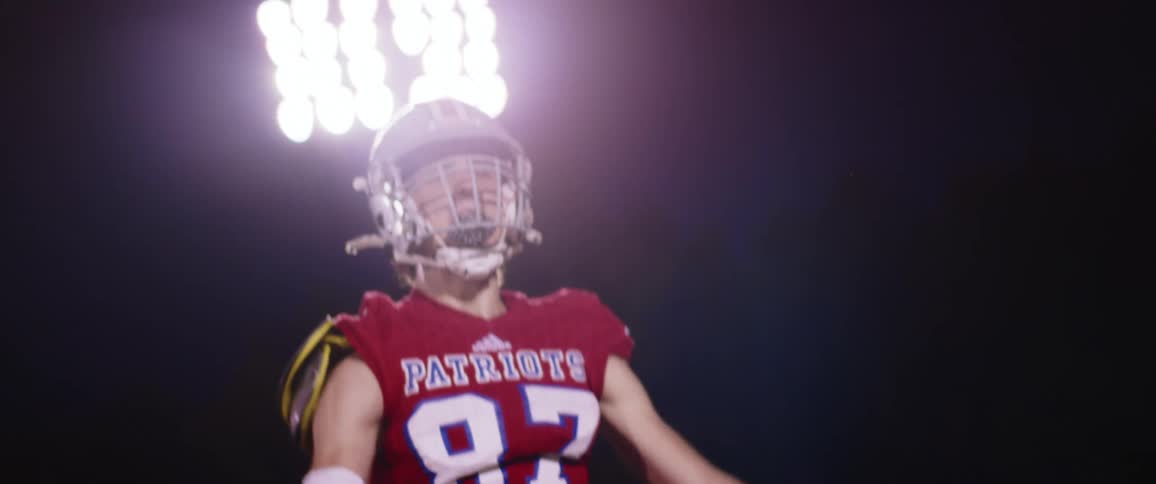 Football player wearing uniform jumps onfield under field lights