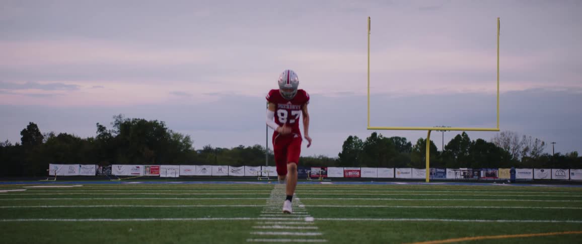 A football player in a red jersey sprinting on an outdoor football field