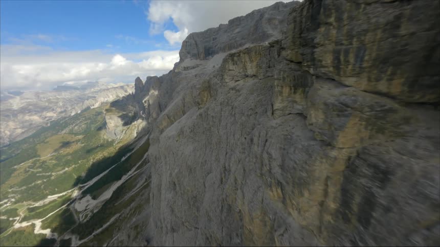 An aerial view of tall rocky cliffs with a lake in the distance