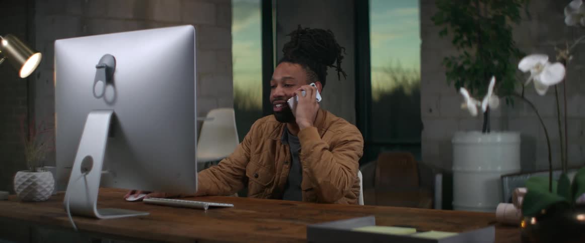 A man is talking on the phone and sitting in his office