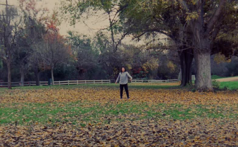 A woman dances in a grassy field