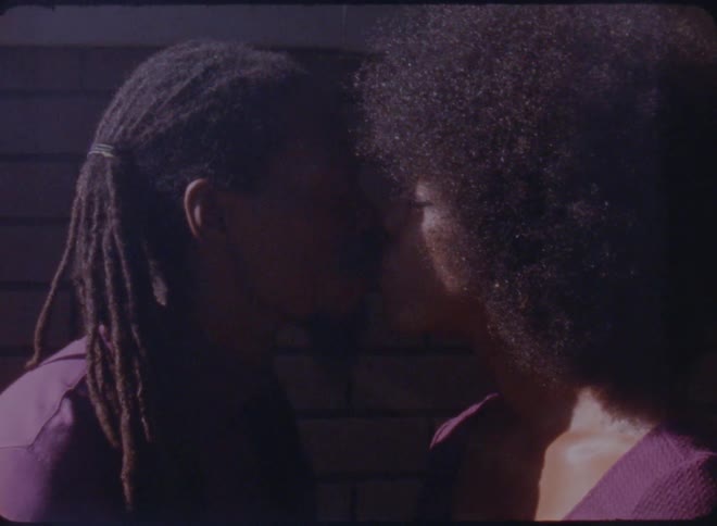 A man and woman kiss and smile at one another