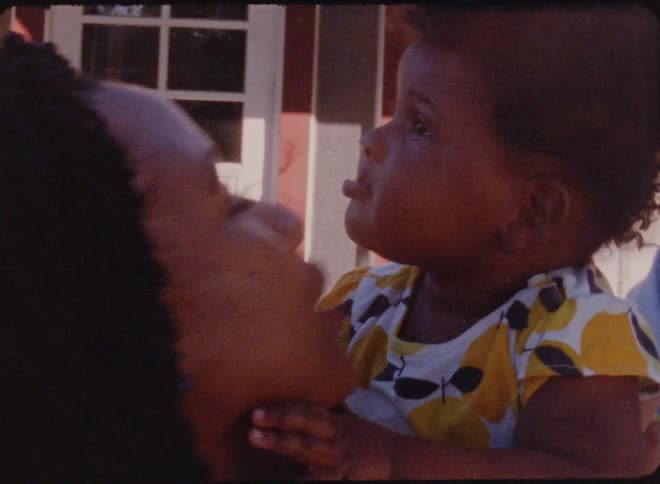 Mother and father are outside their house hugging and kissing their baby girl