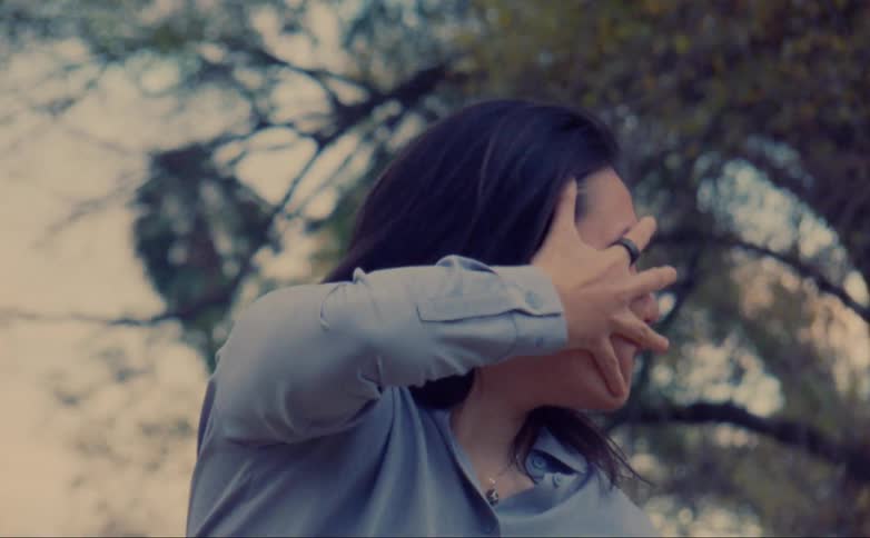 A woman stretches her hand across her face while performing a modern dance