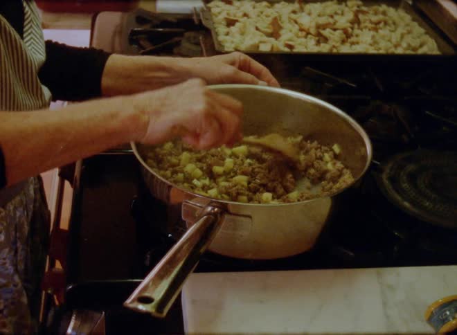 Woman cooking on a pan on the kitchen at home caught on vintage film