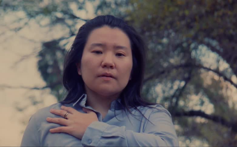 Woman with a hand over her chest breathing deeply looking at the camera caught on vintage film