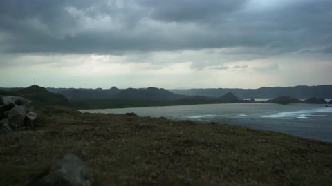Grassy hill ends at the edge of a cliff overlooking water