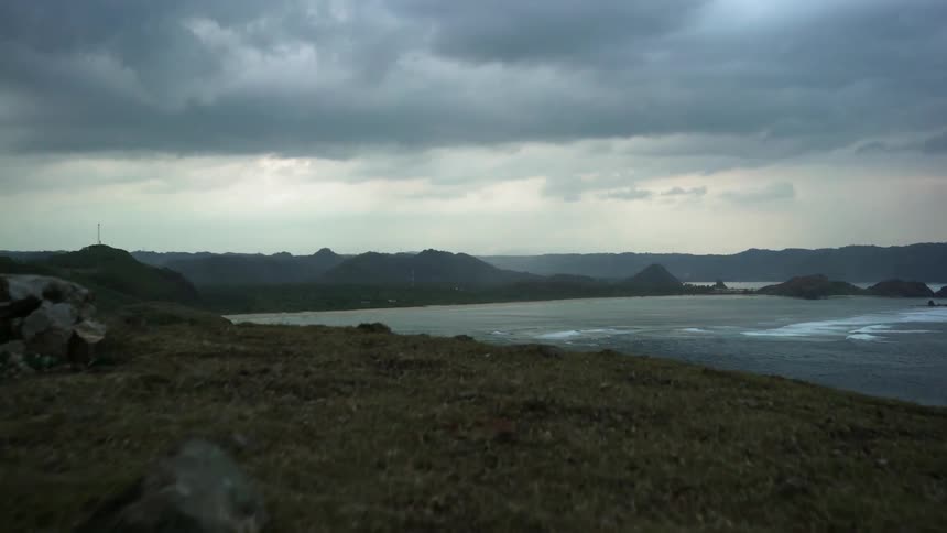 Grassy hill ends at the edge of a cliff overlooking water