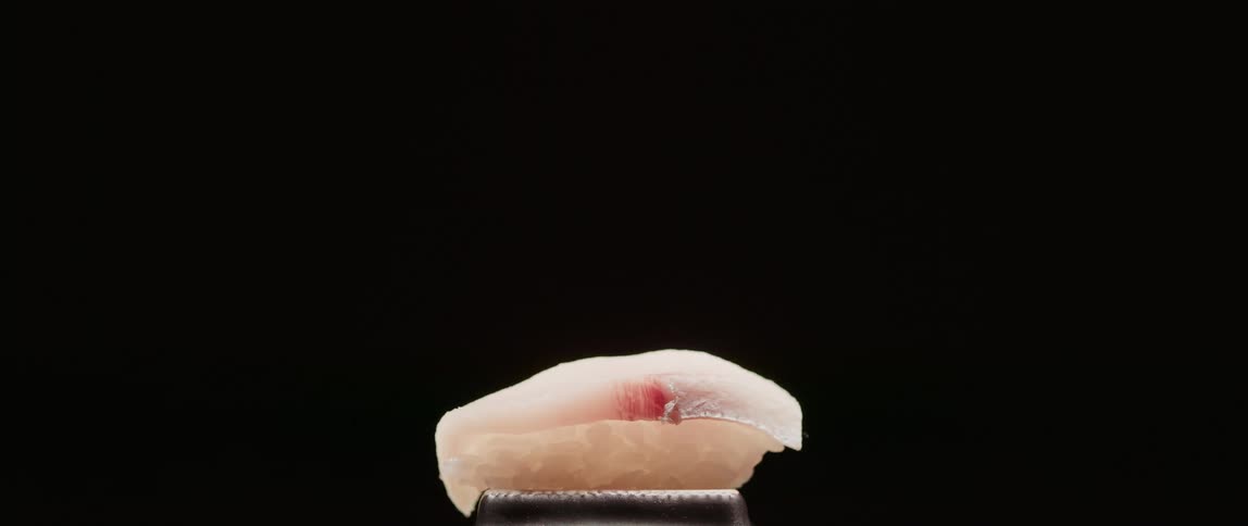 A person uses chopsticks to set down a piece of sushi and then pick it up