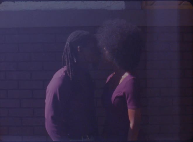 A couple lean in for a kiss outside their house