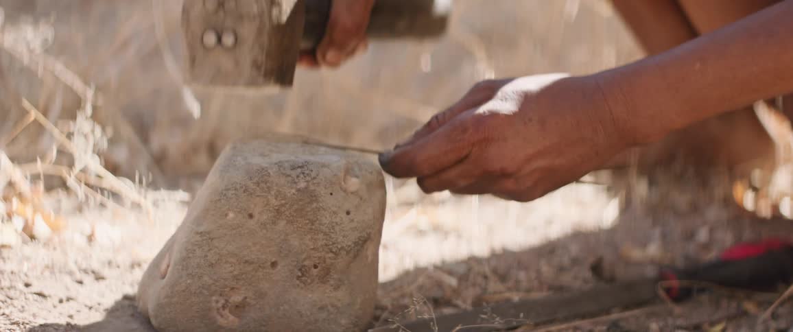 Tribal man hammers arrow for hunting in the field