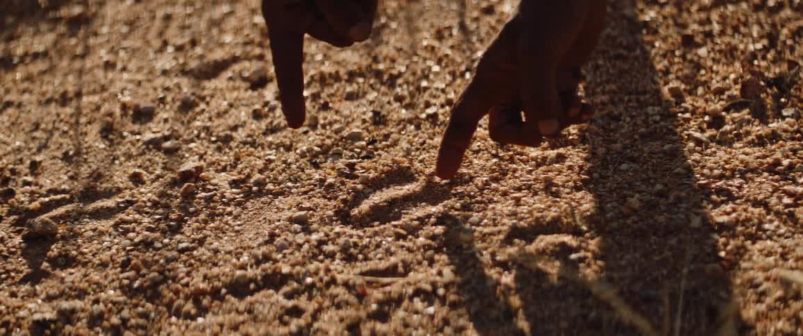 Tribal men point to animal tracks to hunt