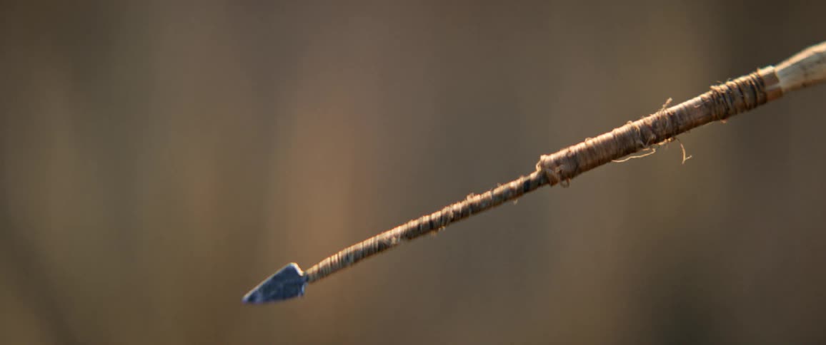 Man holds an arrow and aims as he gets ready to shoot