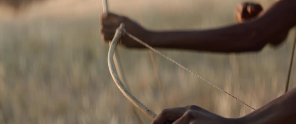 Tribal men shoot bow and arrows in the savannah