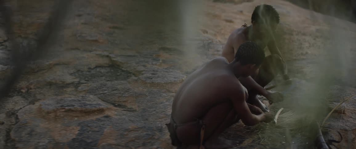 Two indigenous men prepping for an outdoor fire