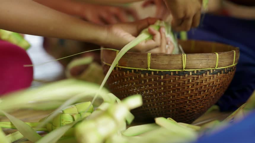 A person packs rice into a green woven box