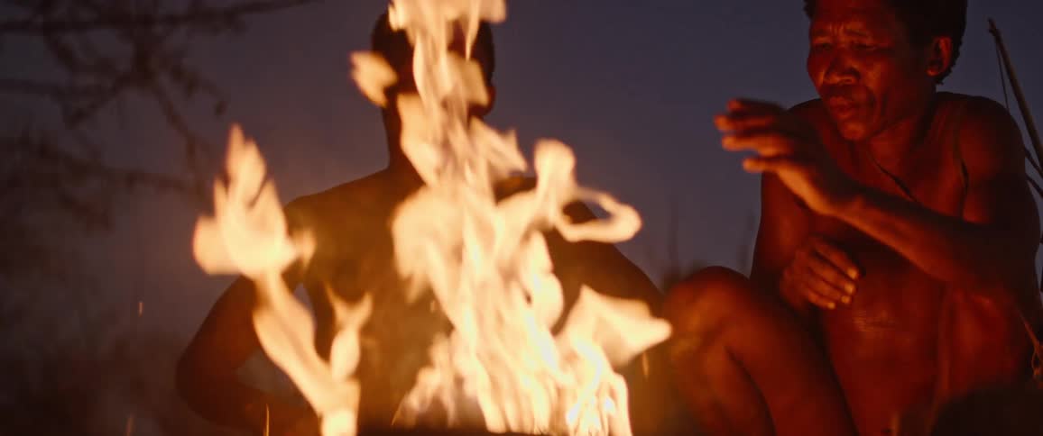 Father and his son sit around a fire in the evening