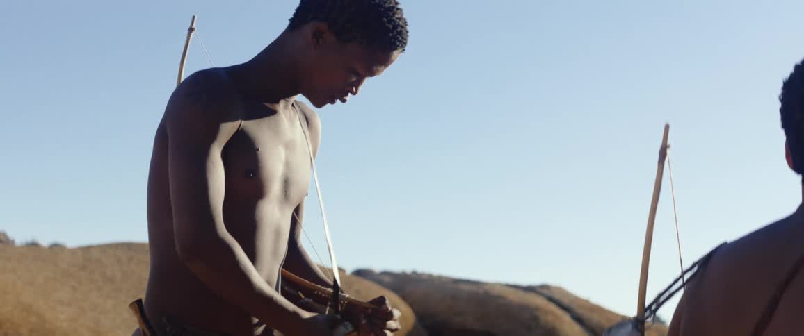 Primitive hunters check bow and arrows in an open field
