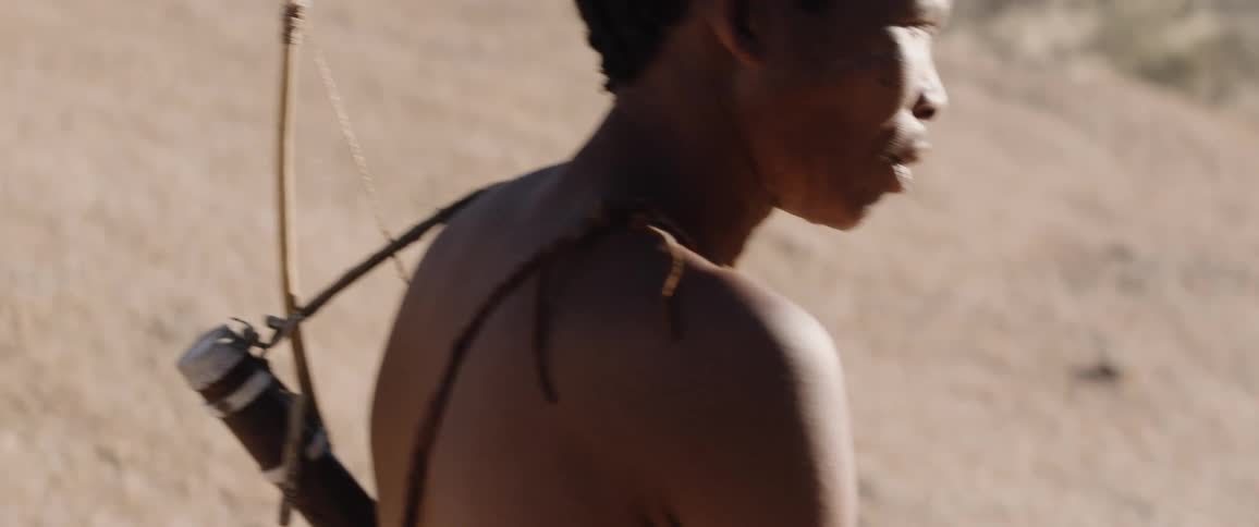 Two young men walk up a hill with bows and arrows