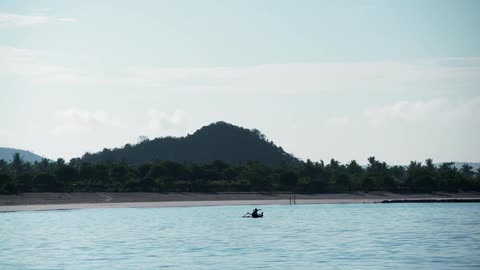 A person paddles a boat near the shore