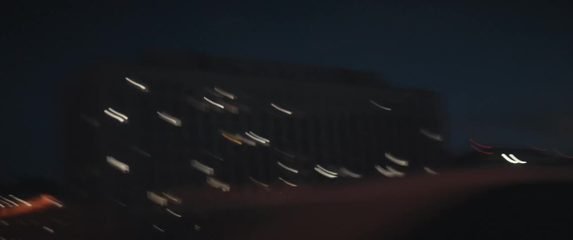 Palm trees and city apartment buildings seen from a moving car at night