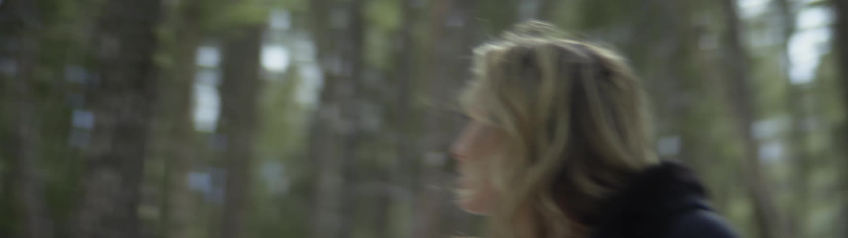 A woman is walking through the woods and looks lost