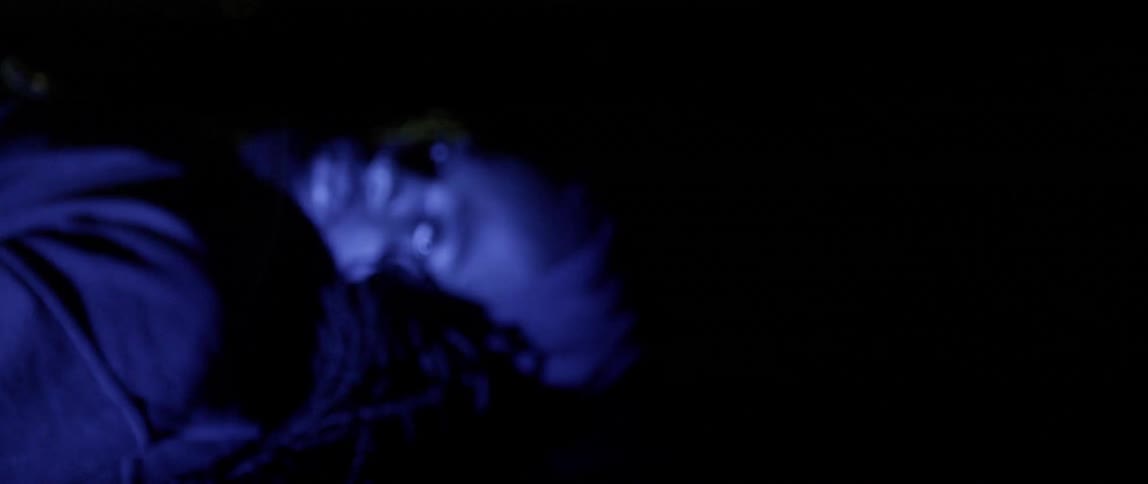 A man lies on the ground while red and blue lights flash