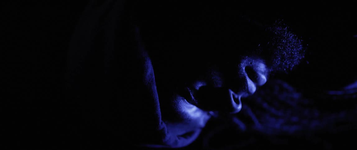 Red and blue lights flash on a man's face in the dark